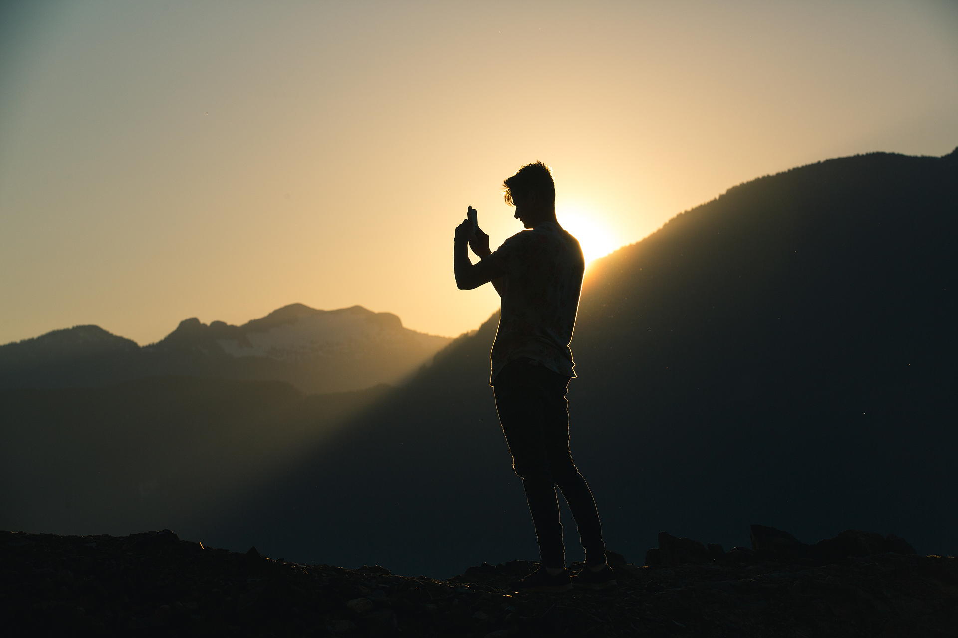 Silhouette Of Person Taking A Photo On A Mountain